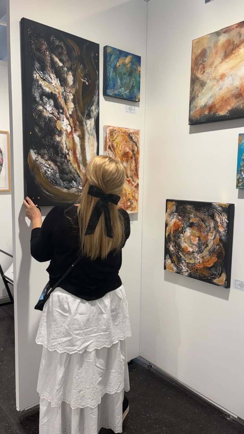 Ildik&oacute; Simon adjusting one of her canvases on the exhibition wall